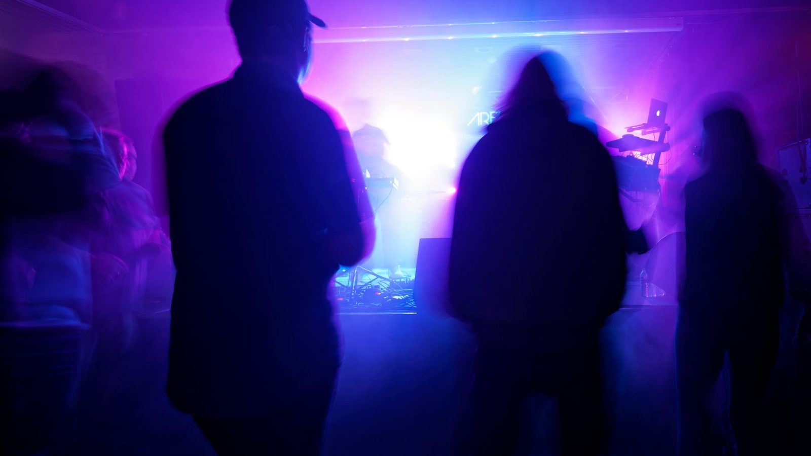 Guests in purple haze at an underground Night of Events party